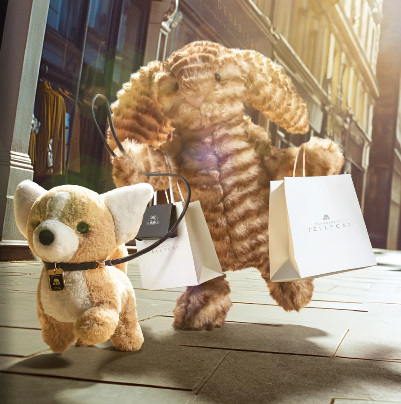 Jellycat bunny is walking a dog while carrying a Jellycat logo bag. 