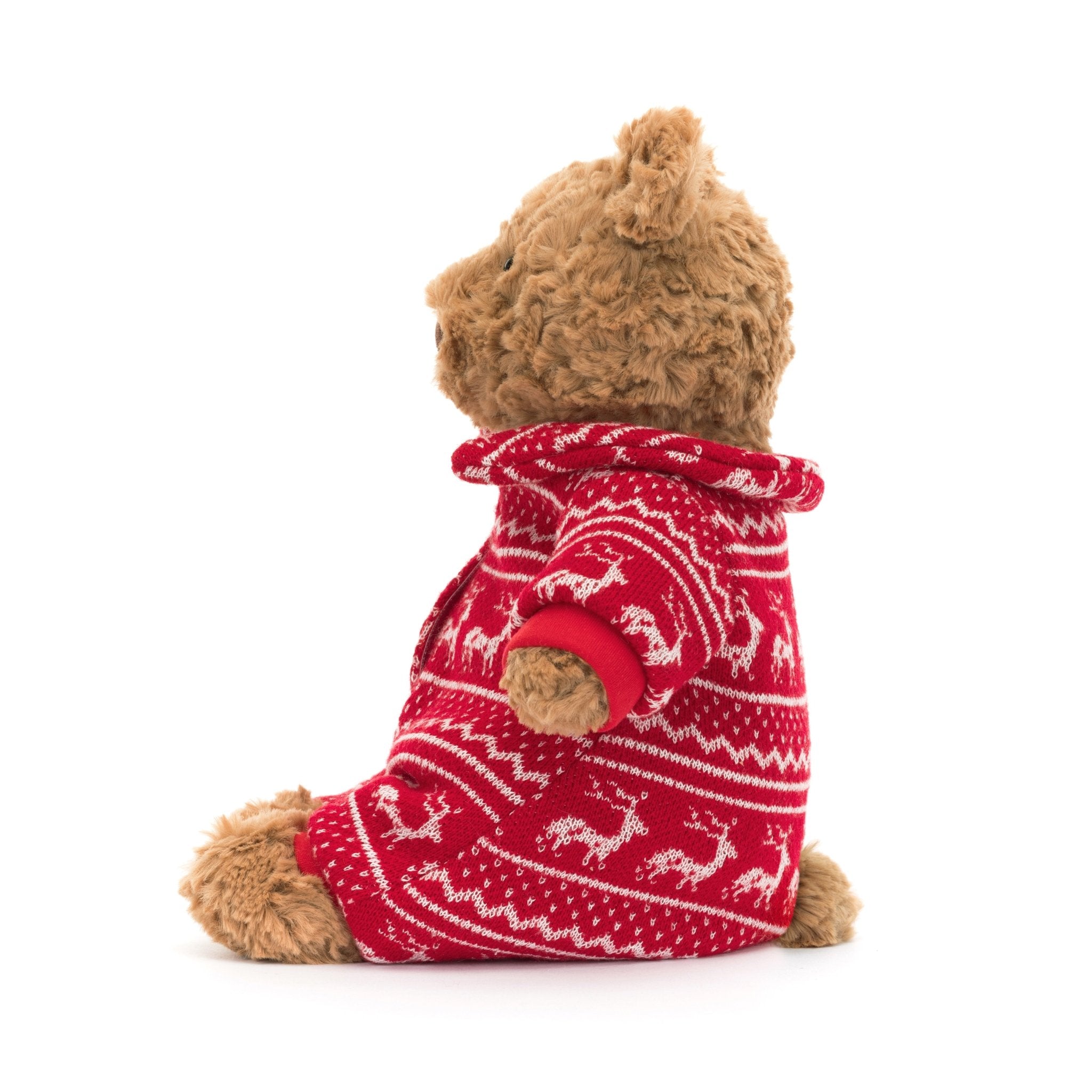 Bartholomew Bear Winter Pajamas - TAYLOR + MAXJellycat - A brown teddy bear turned to the side, wearing red pajamas, featuring white reindeers